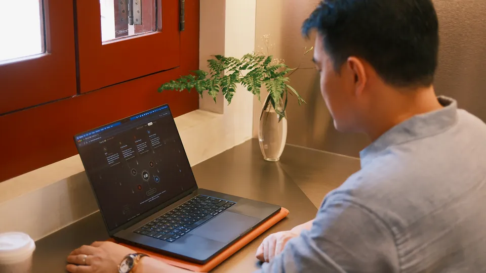 Sean Chan at his laptop by a red lacquered window, a chart open on the screen